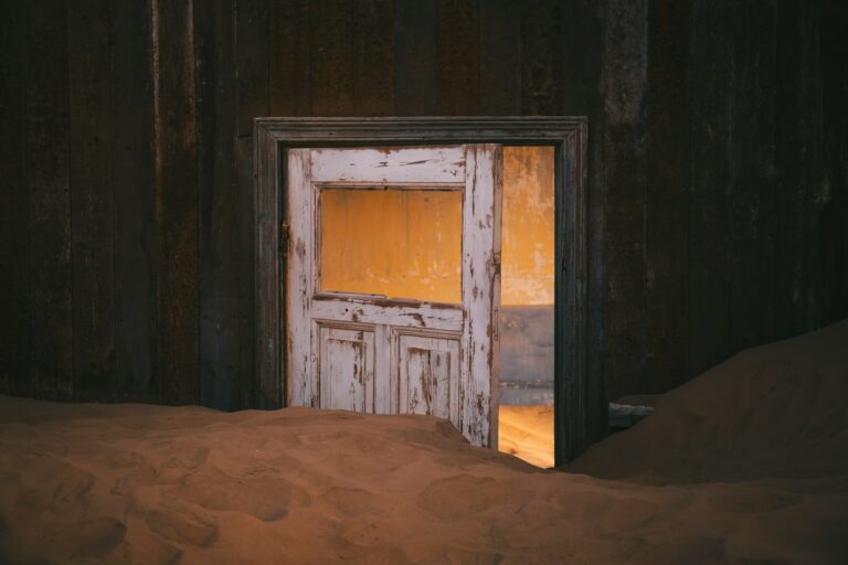 A picture with a door and sand.